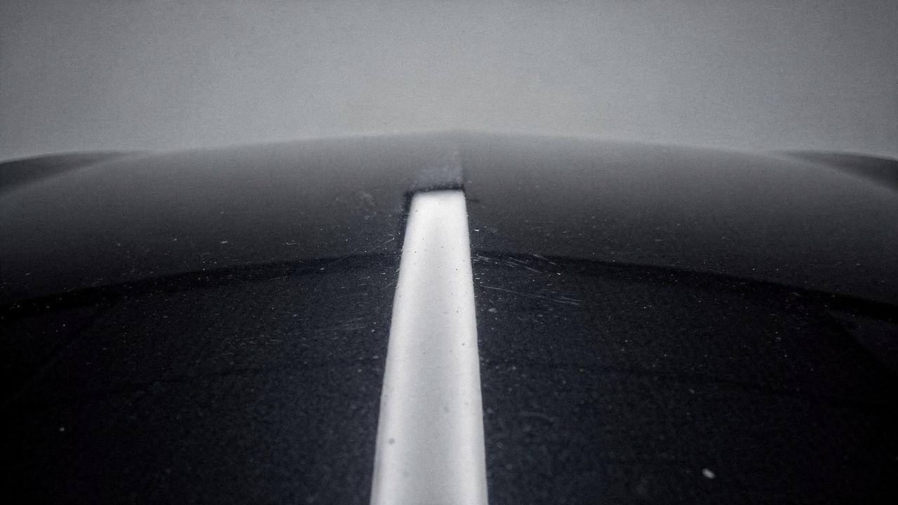Bonnet of a dark sedan before corrective detailing, clear coat dulled and hazed